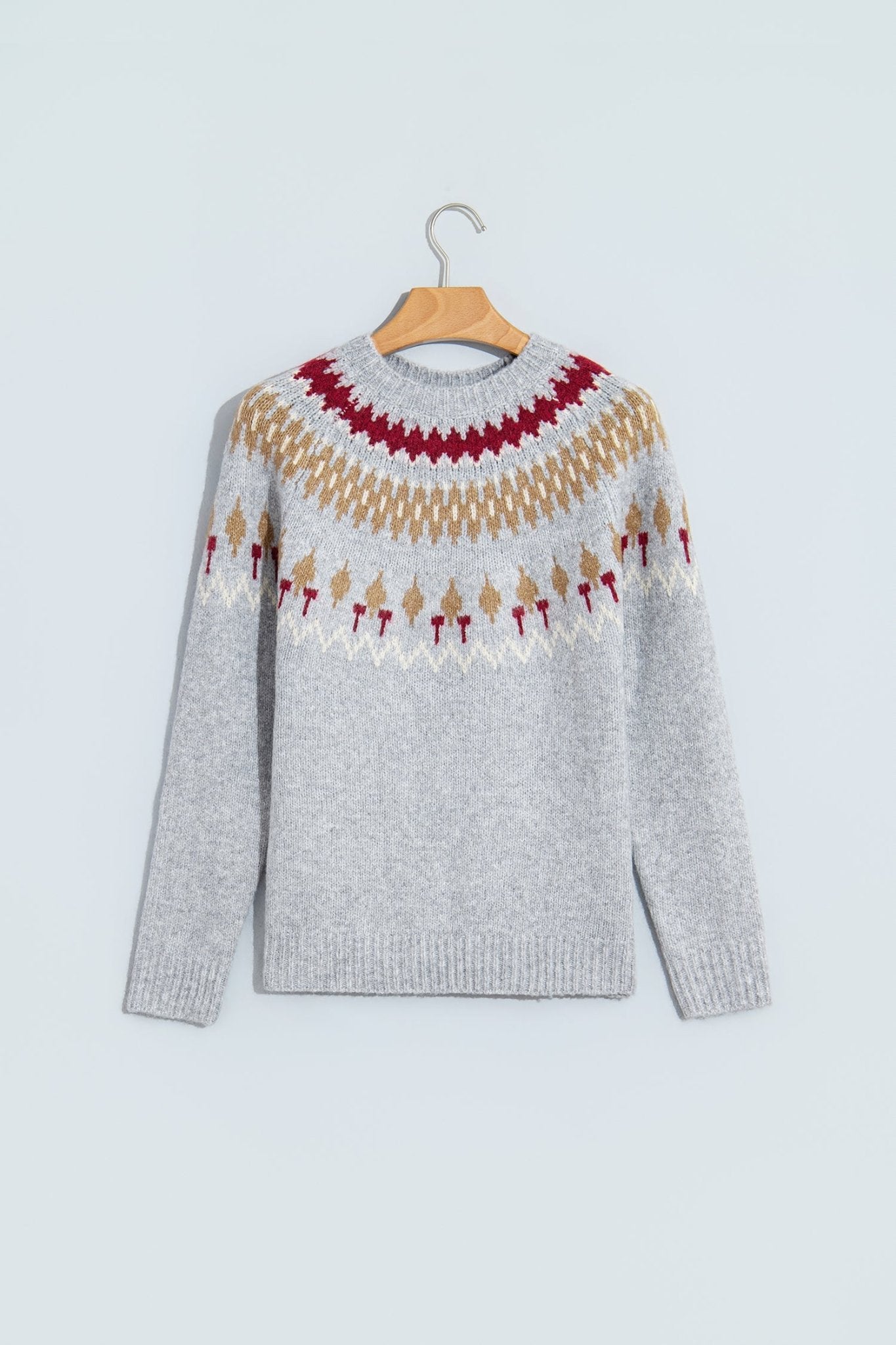 Light gray Fair Isle knit sweater with red, beige, and white pattern on hanger.