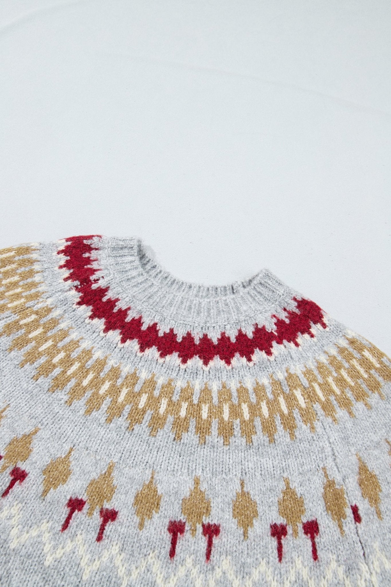 Close-up of gray knit sweater with red geometric yoke and tan-red Fair Isle motif.