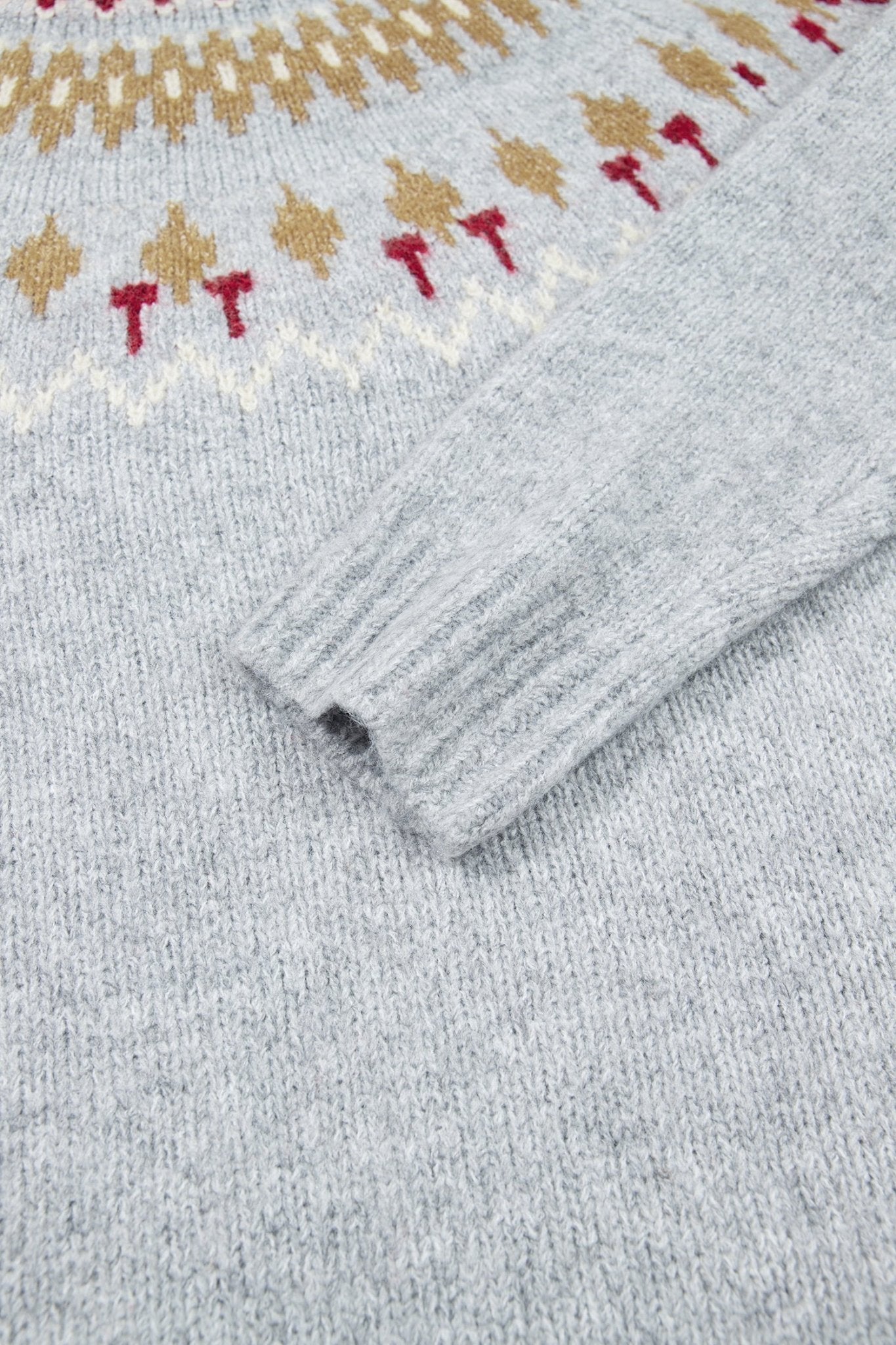 Close-up of gray Fair Isle knit sweater with gold-red details and ribbed.