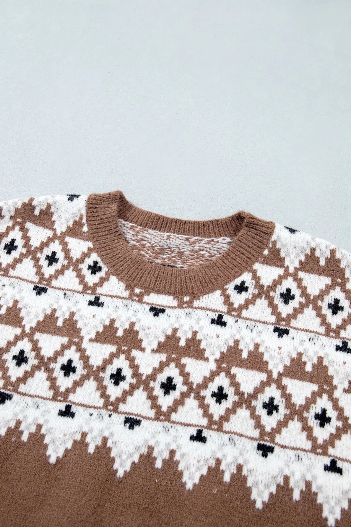 Close-up of brown ribbed crewneck sweater with white and black Fair Isle geometric pattern.