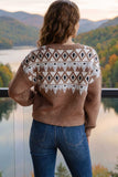 Woman seen from behind in brown geometric knit sweater overlooking a scenic mountain lake view.