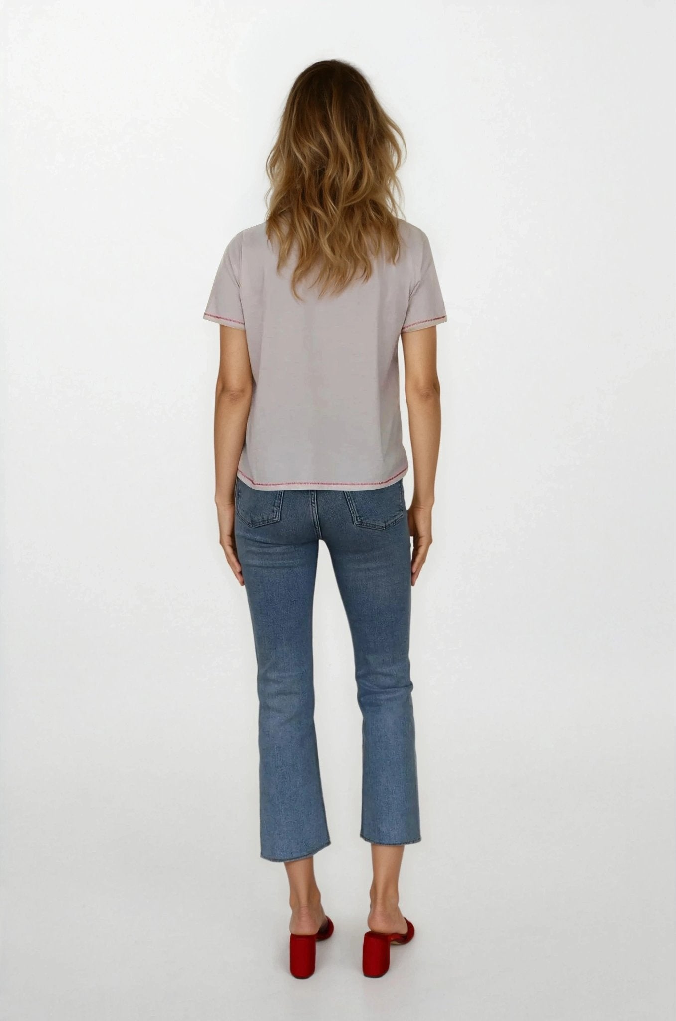 Woman wearing a light gray t-shirt and blue jeans on a white background