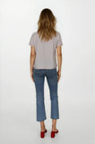 Woman wearing a light gray t-shirt and blue jeans on a white background