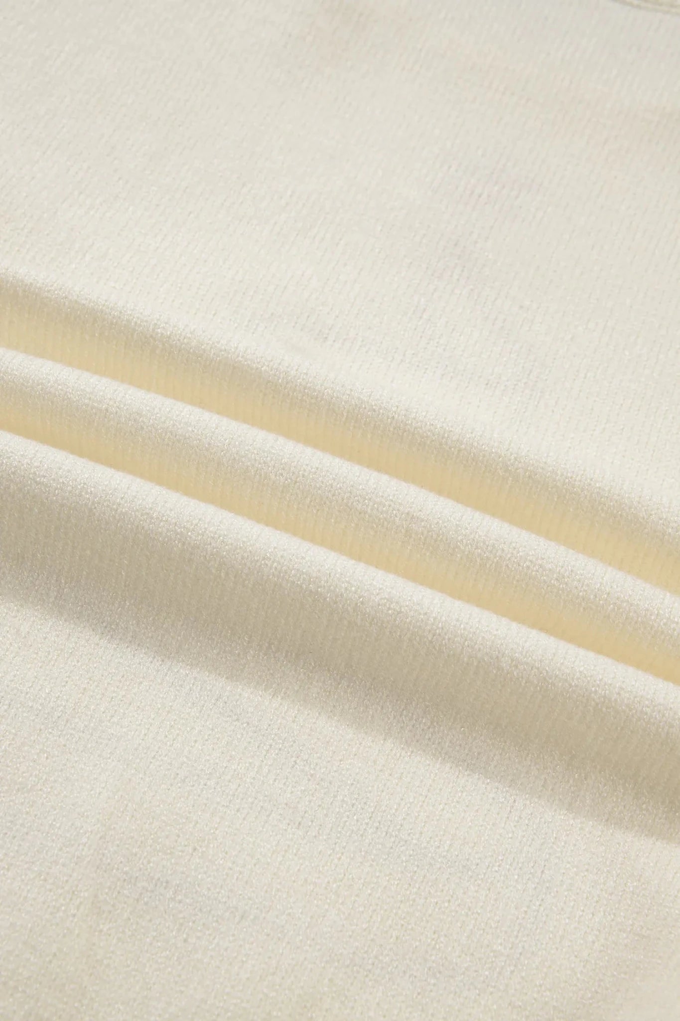 A close-up of draped cream-colored fabric with a soft, fine texture and gentle folds.