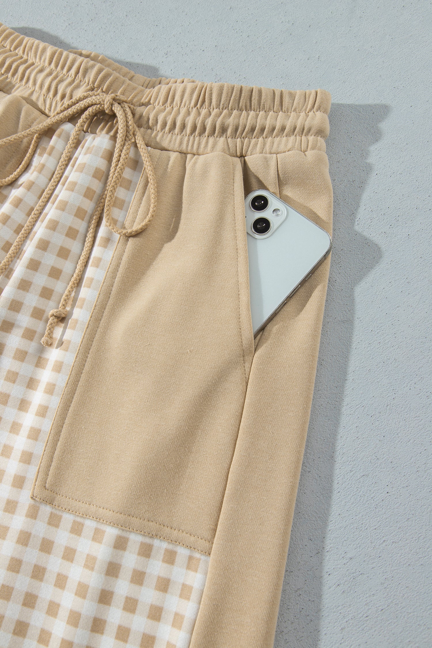 Khaki gingham pants patch pocket holding a phone