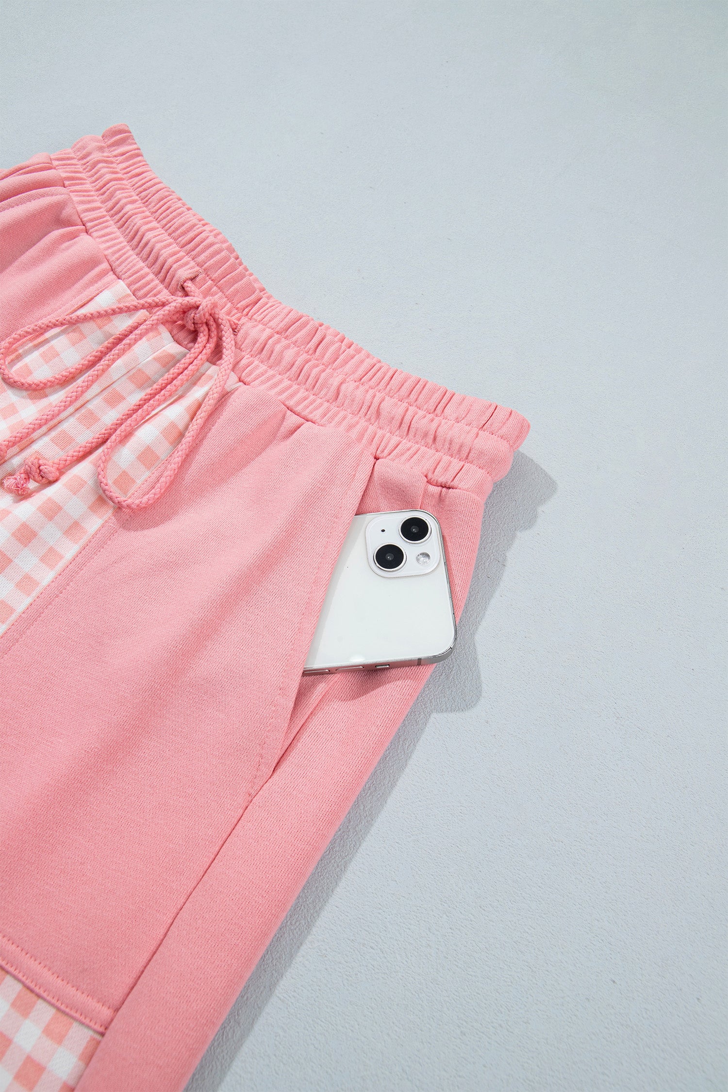 Pink gingham pants patch pocket holding a phone