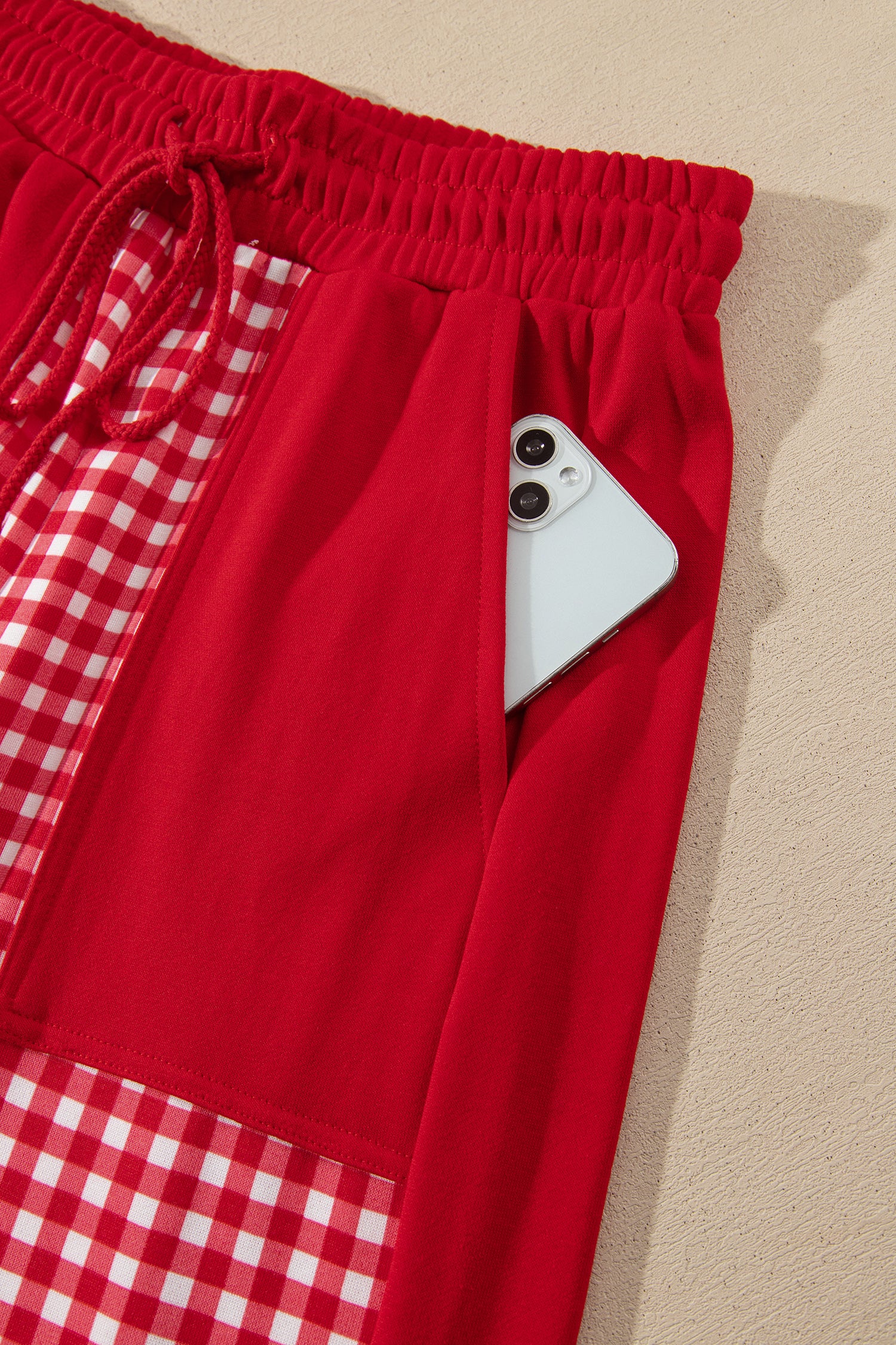 Red gingham pants patch pocket holding a phone