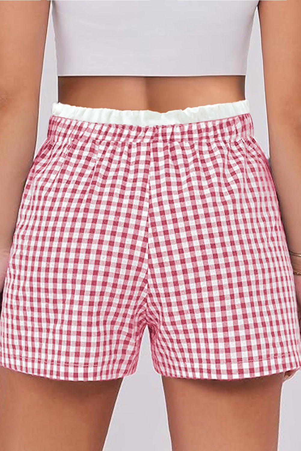Red and white checkered shorts worn by a person on a plain background