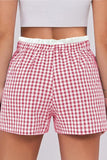 Red and white checkered shorts worn by a person on a plain background