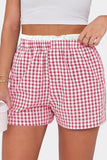 Red and white checkered shorts worn by a person on a plain background