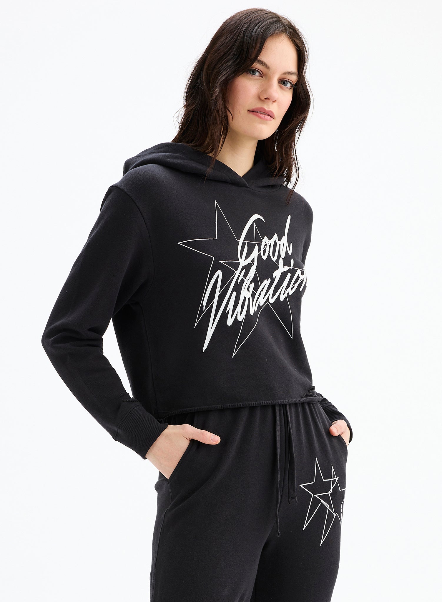 Woman wearing a black hoodie with 'Good Vibration' text and star design on a white background