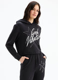 Woman wearing a black hoodie with 'Good Vibration' text and star design on a white background