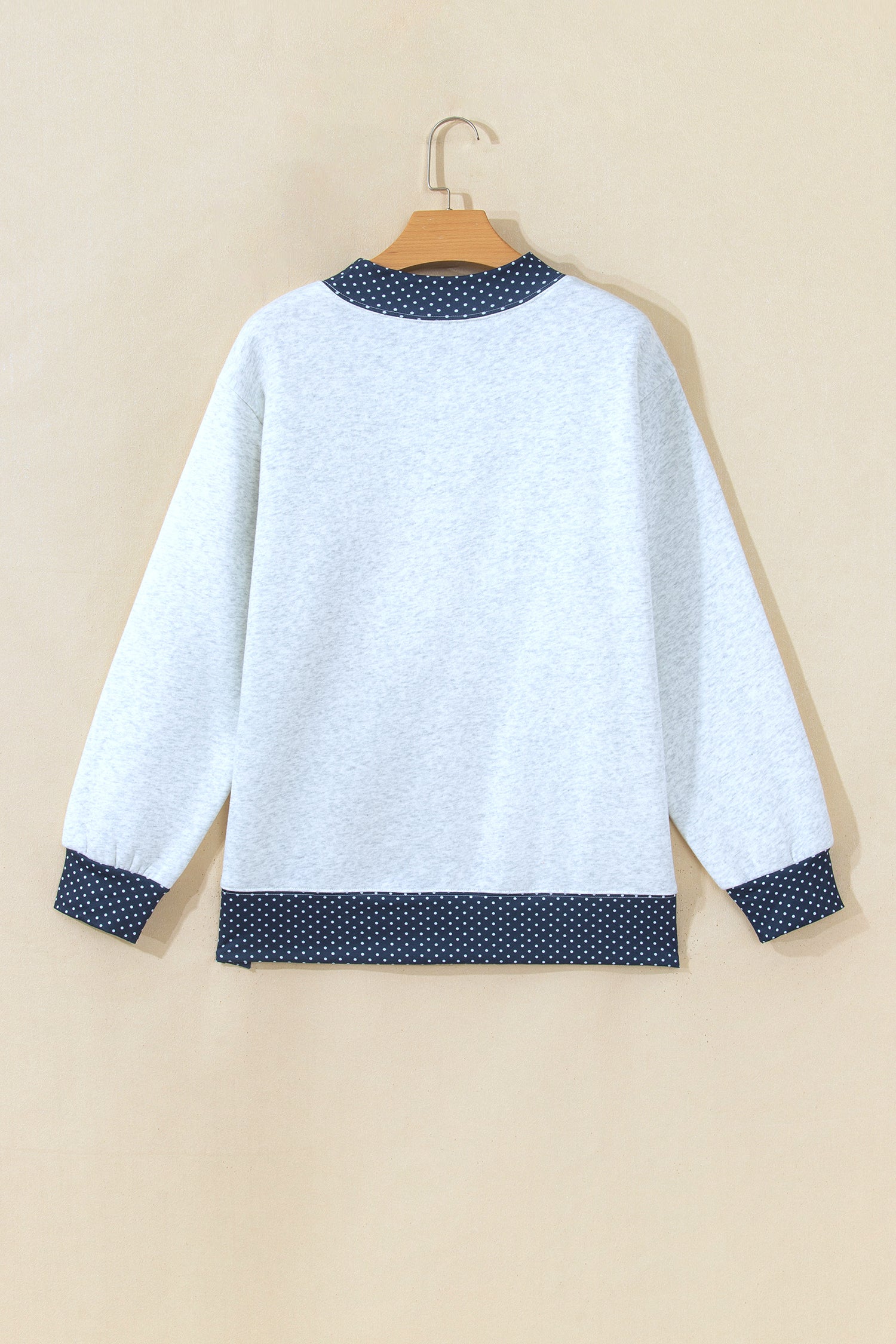 Gray sweatshirt with navy polka dot trim on hanger, back view