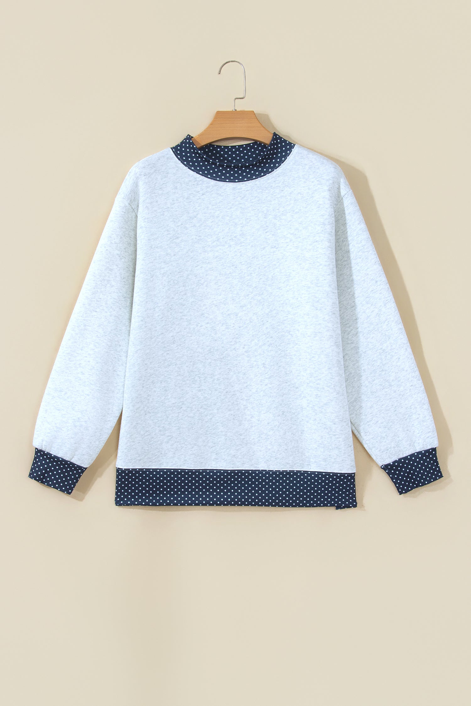 Gray sweatshirt with navy polka dot trim on hanger, front view