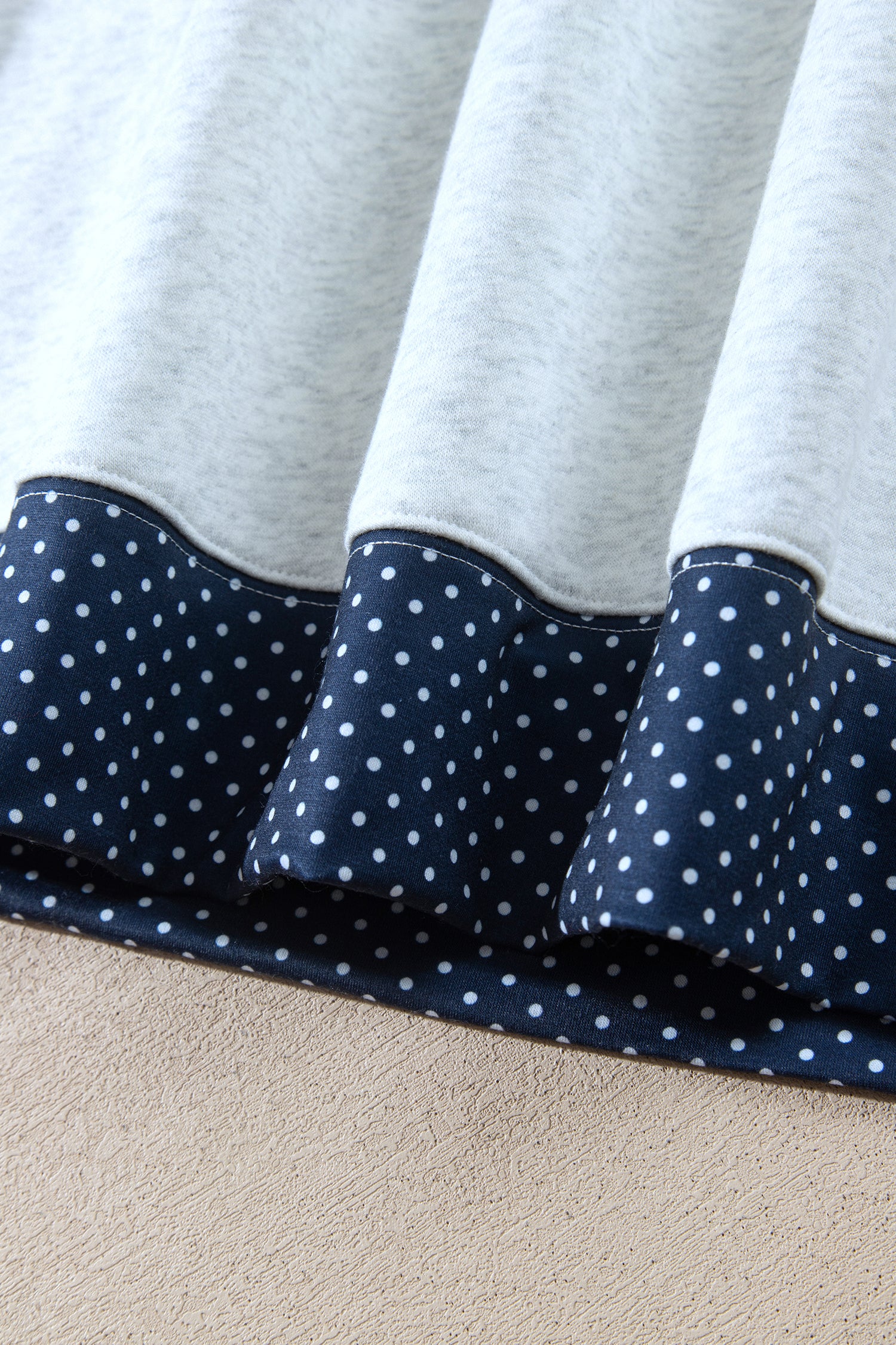 Navy polka dot hem band on gray sweatshirt, close-up