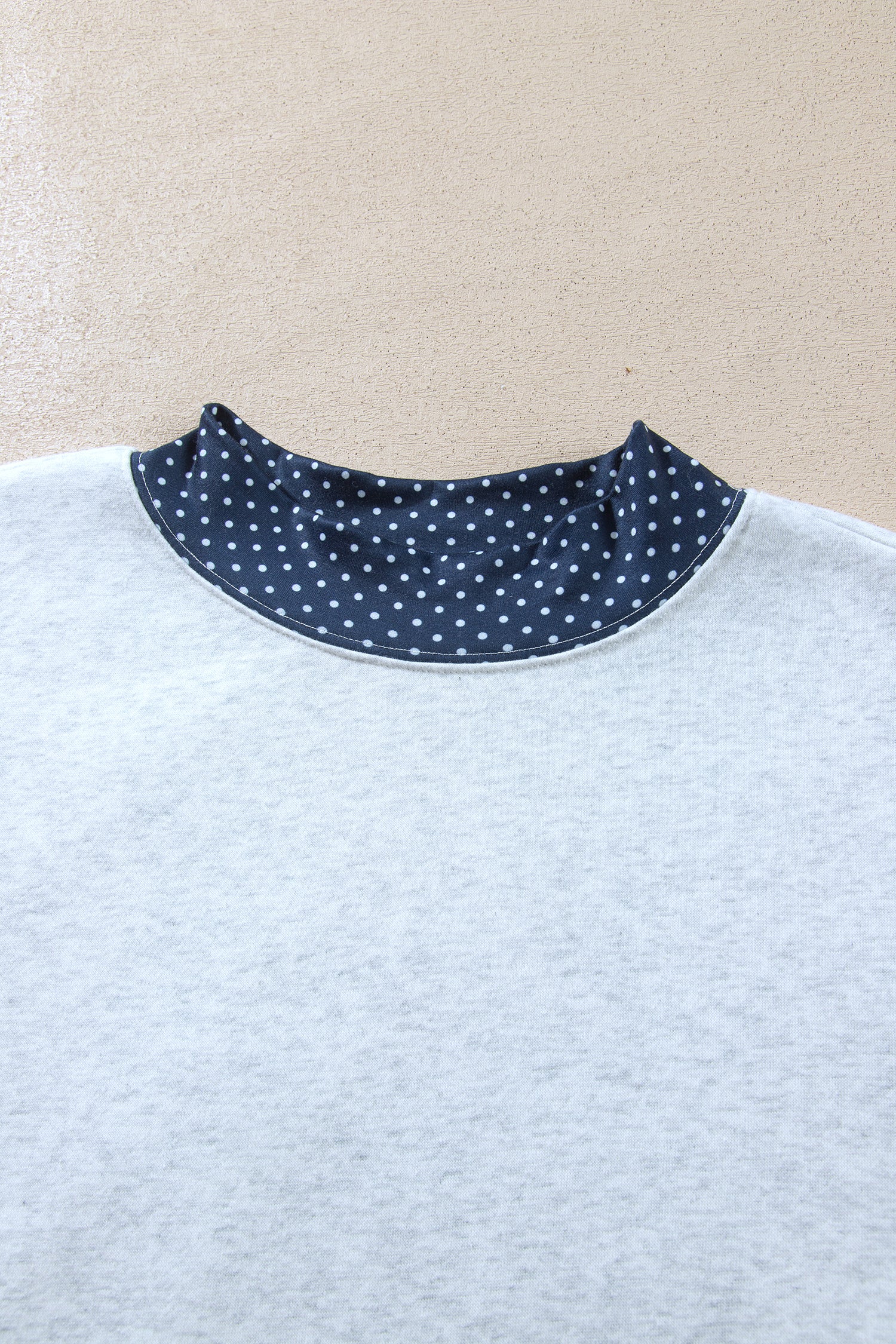Navy polka dot high neck trim on gray sweatshirt, close-up