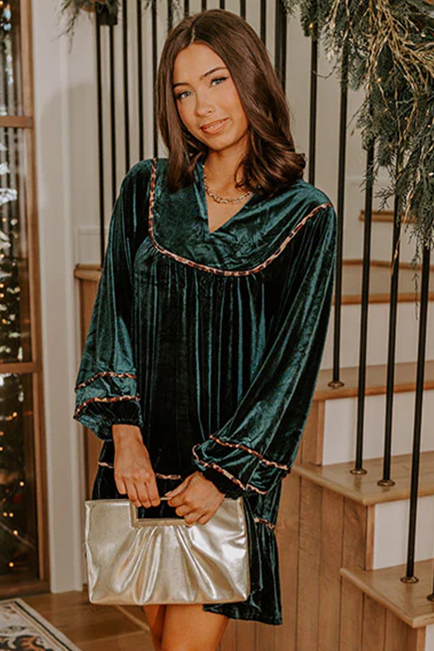 Woman in green velvet leopard trim balloon sleeve dress with a gold clutch