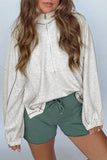 Person wearing a light gray zip-up sweatshirt and green shorts on a plain background
