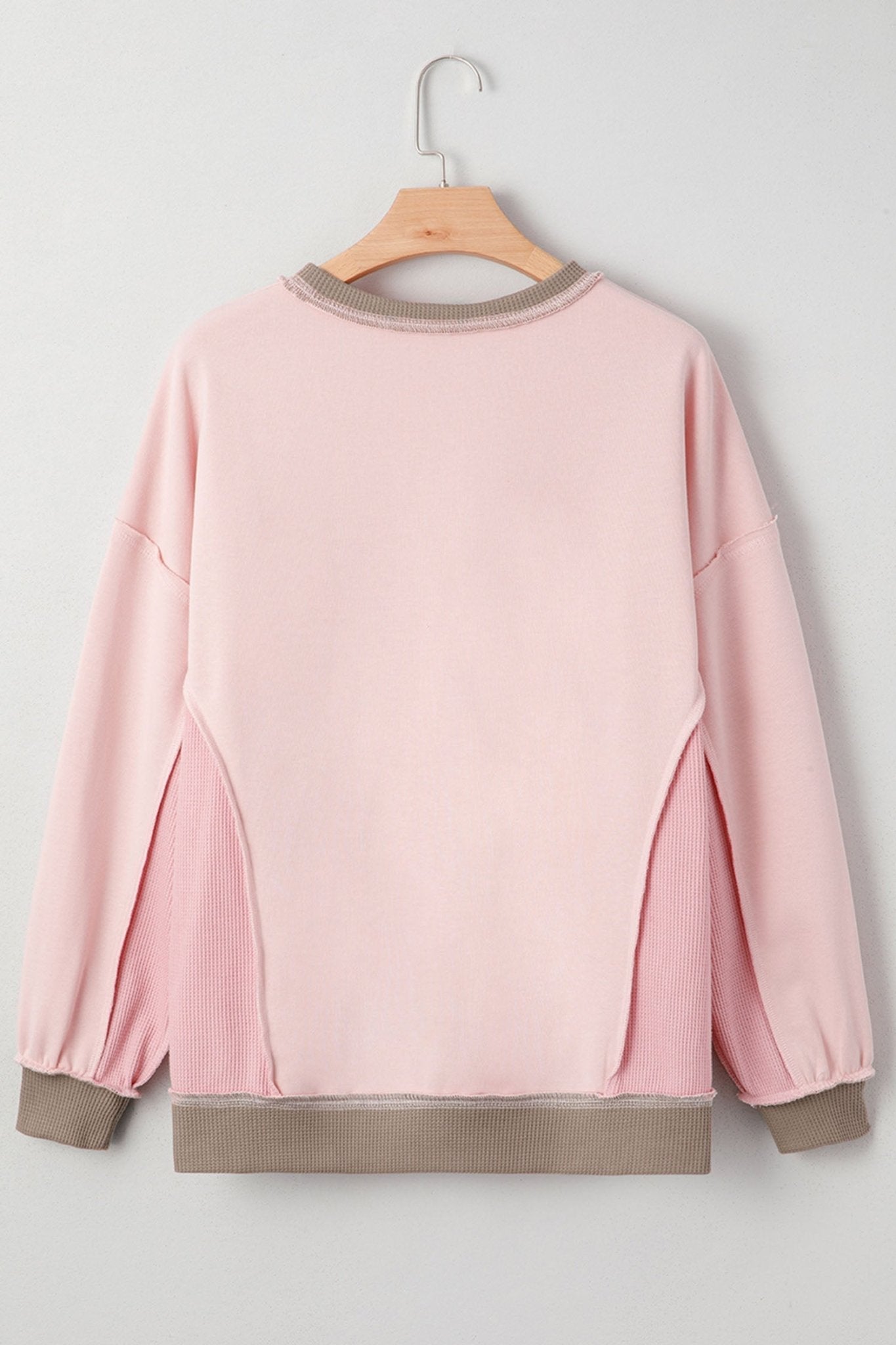 Pink sweatshirt on a wooden hanger against a white background