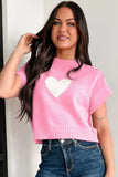 Woman wearing a pink sweater with a white heart design against a plain background