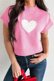 Person wearing a pink sweater with a white heart design on a plain background