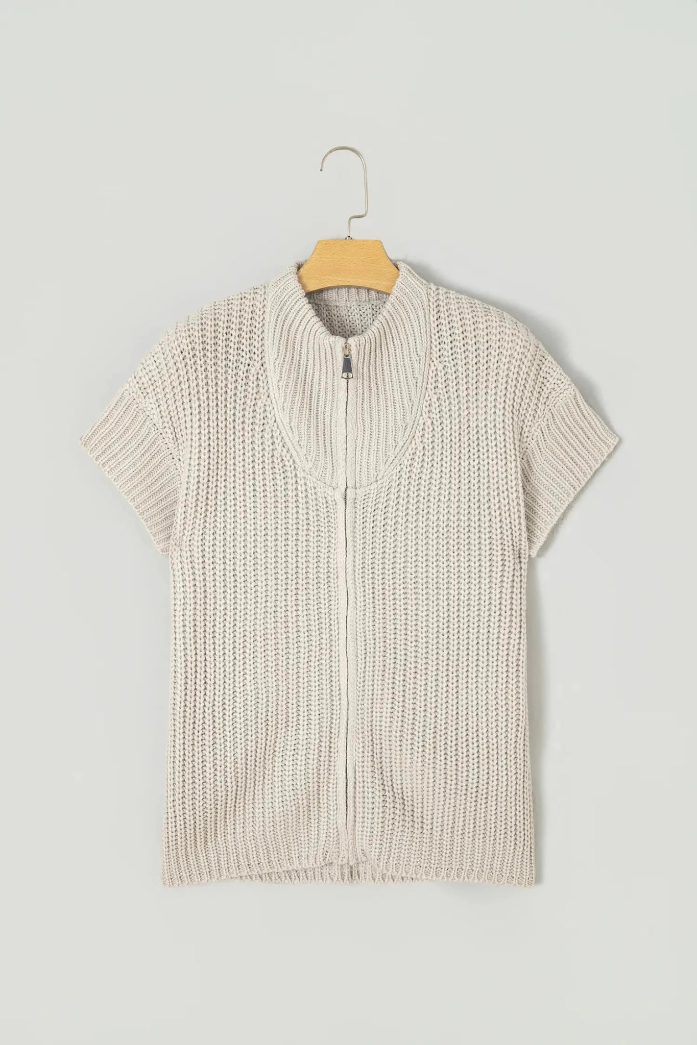 Light oatmeal beige short-sleeve knit zip vest on a wooden hanger.