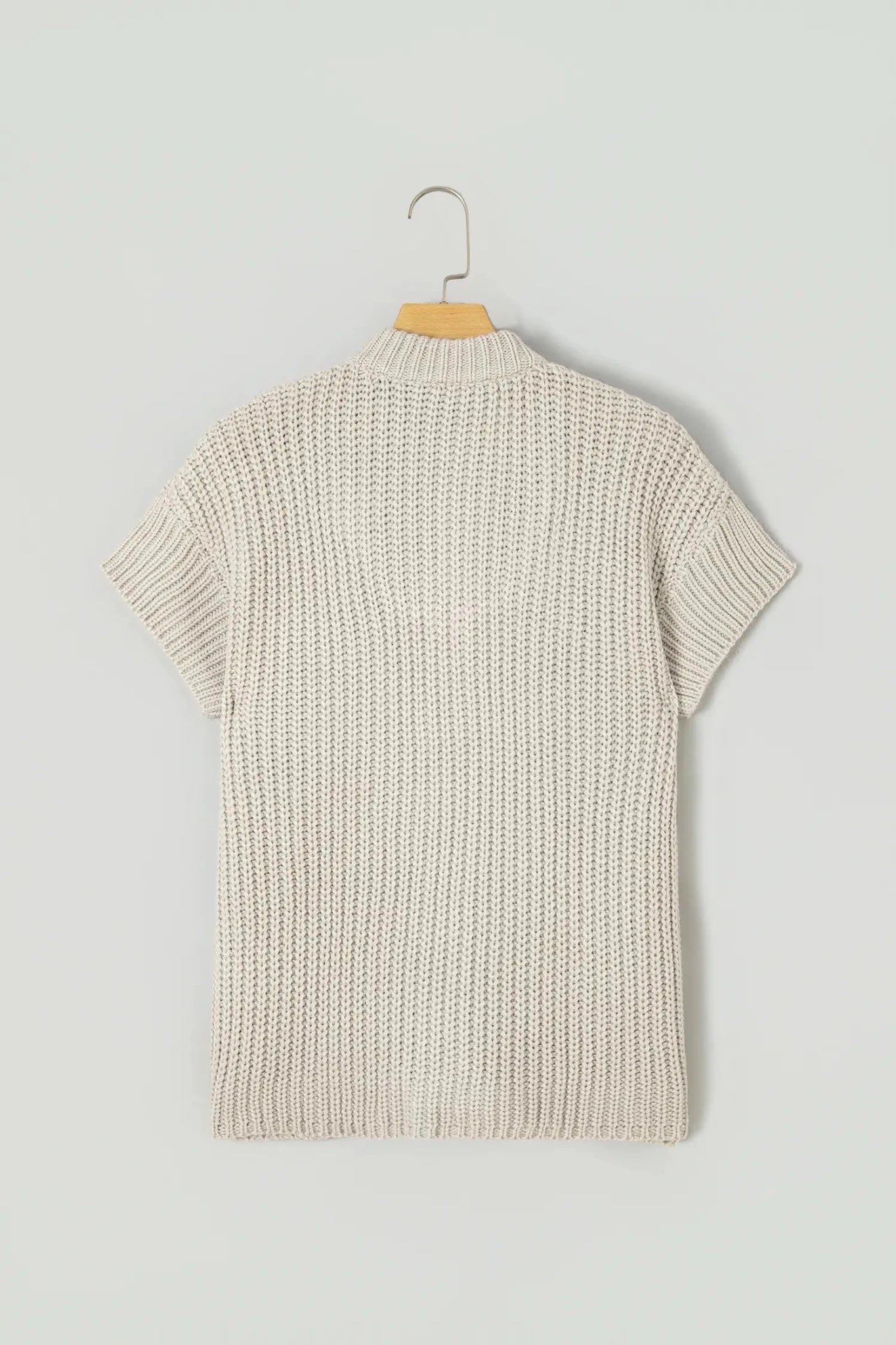 Light cream short-sleeve knit top shown from the back on a wooden hanger.
