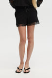 Person wearing black shorts with lace trim on a white background