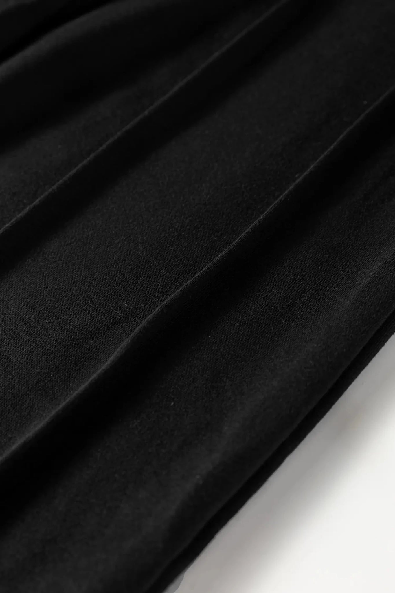 Close-up of black pleated fabric with a white background