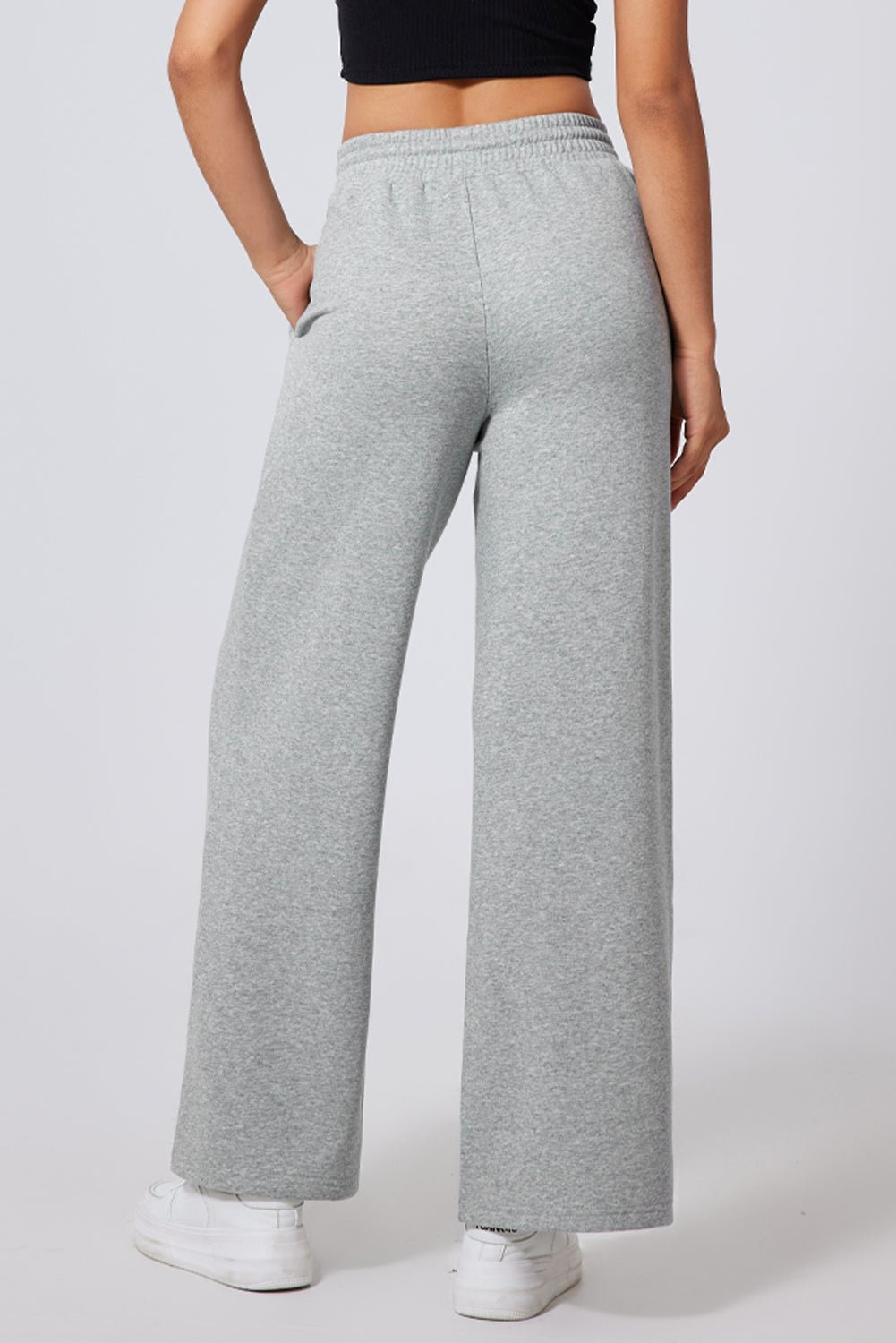 Person wearing gray sweatpants on a plain background