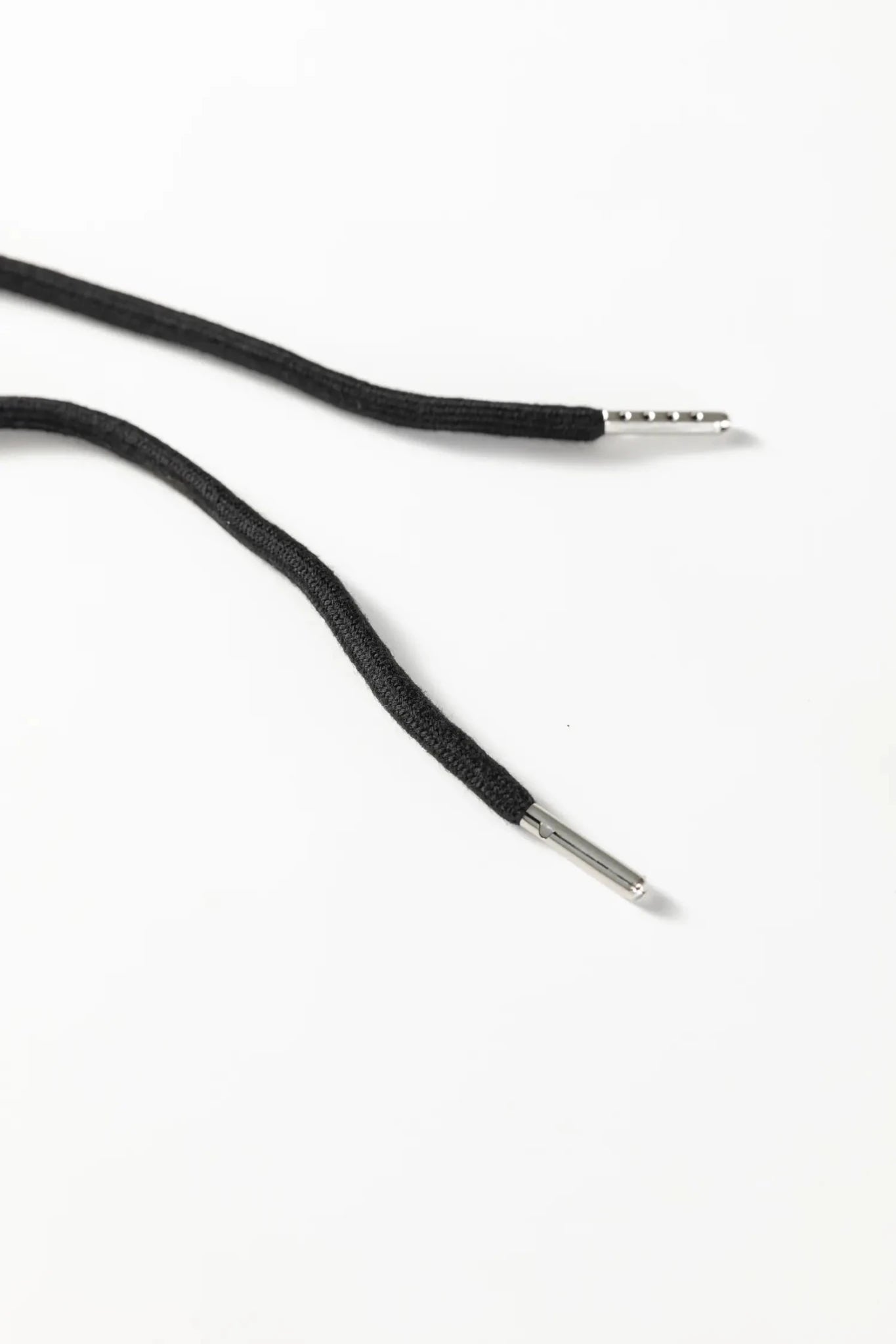 Close-up of black braided cord ends with silver metal tips on a plain white background.