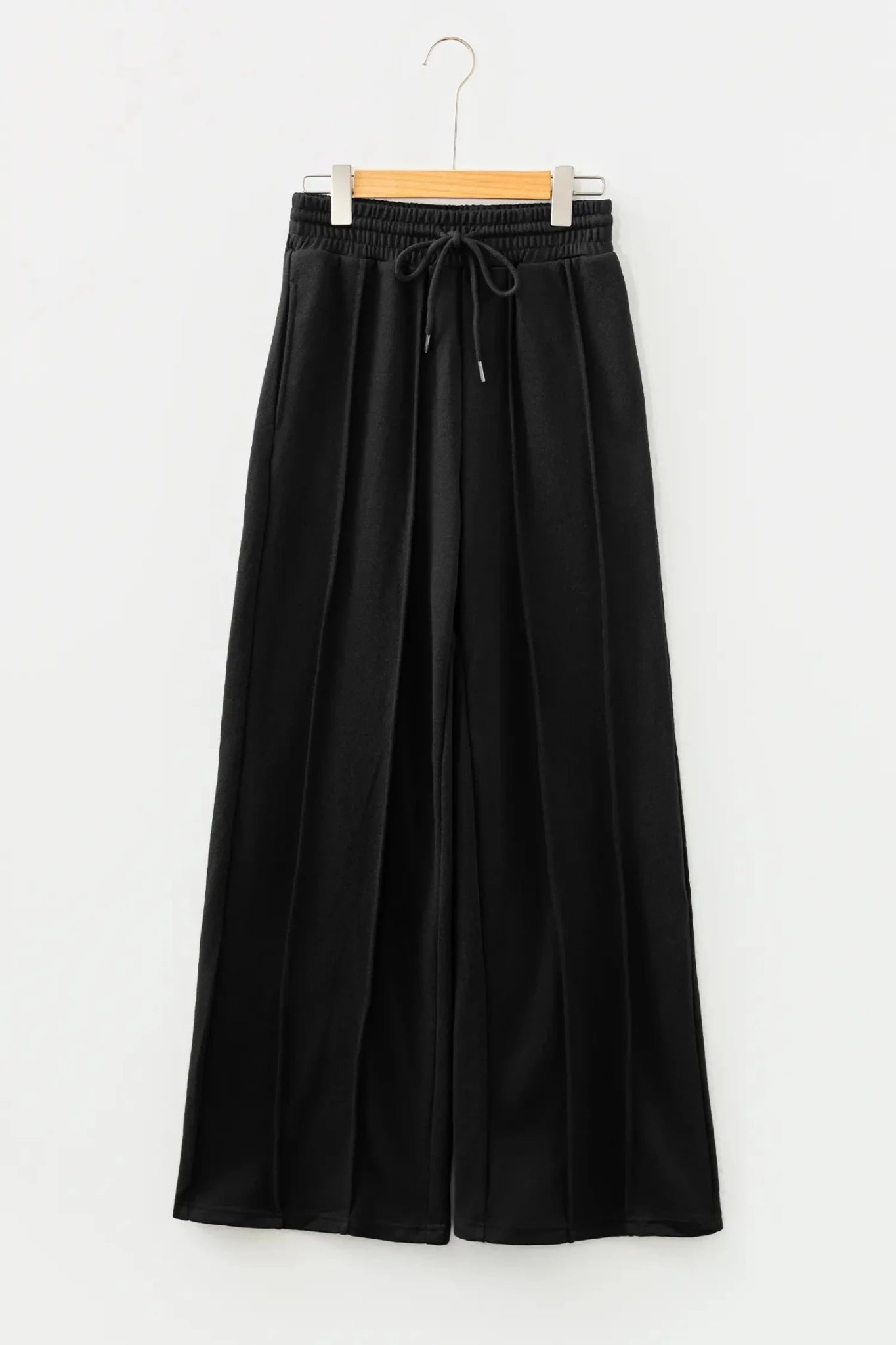 Black wide-leg cropped pants with elastic drawstring waist on wooden hanger.
