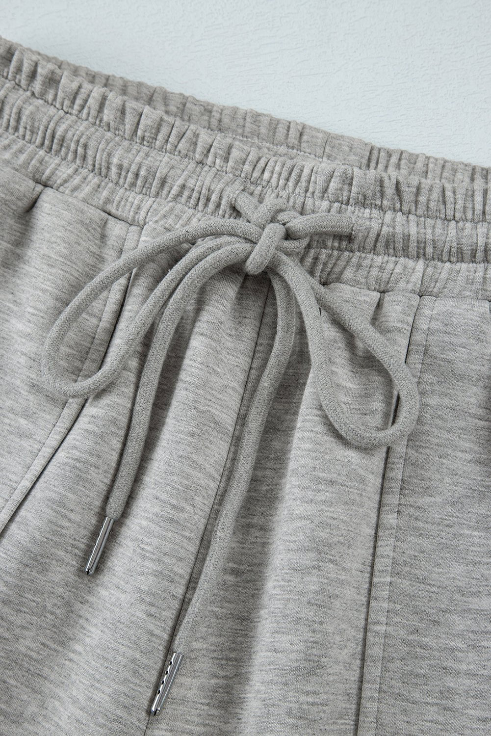 Close-up of gray sweatpants with a drawstring on a light gray background