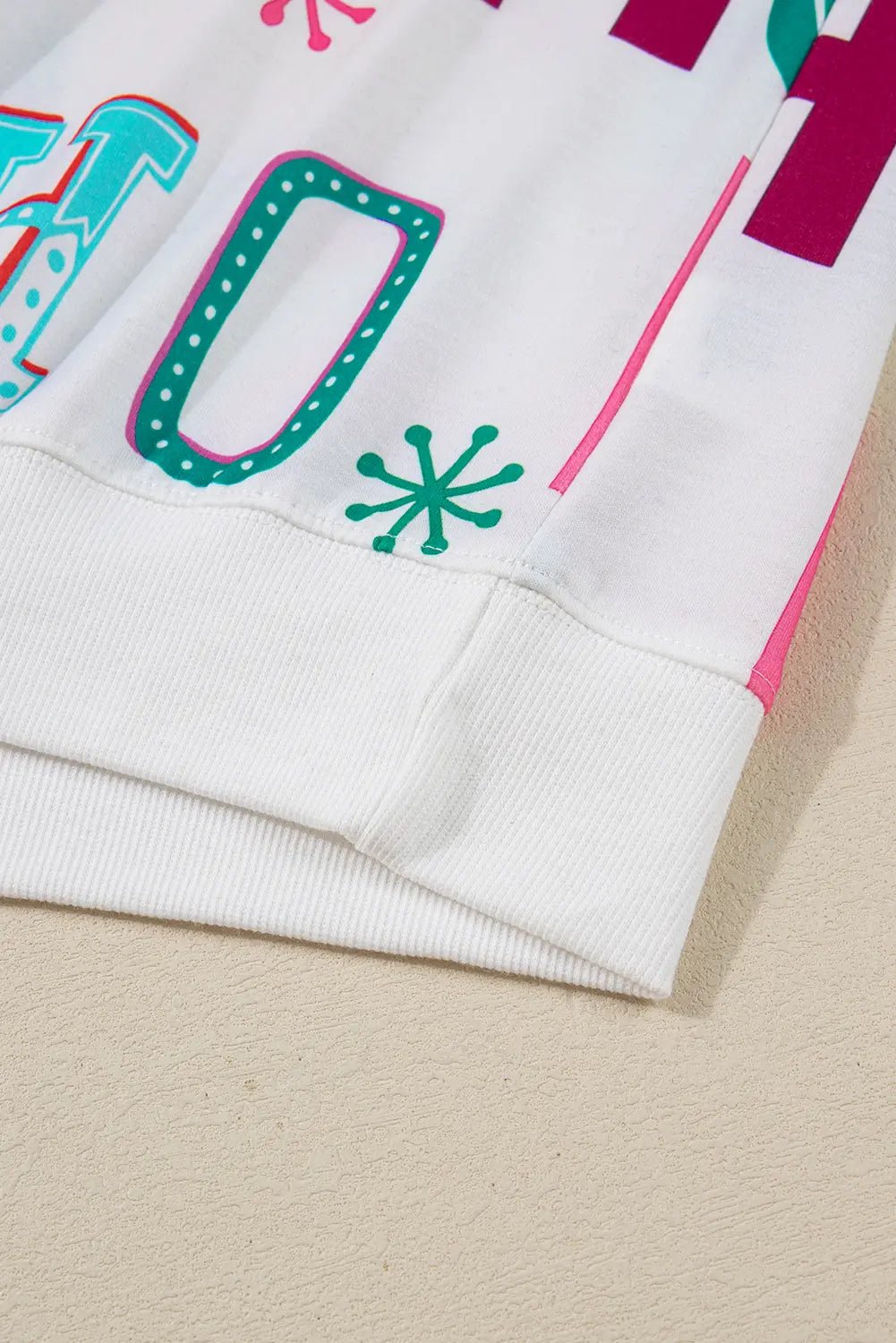 Close-up of a white ribbed sleeve with colorful teal, pink, and magenta lettering.