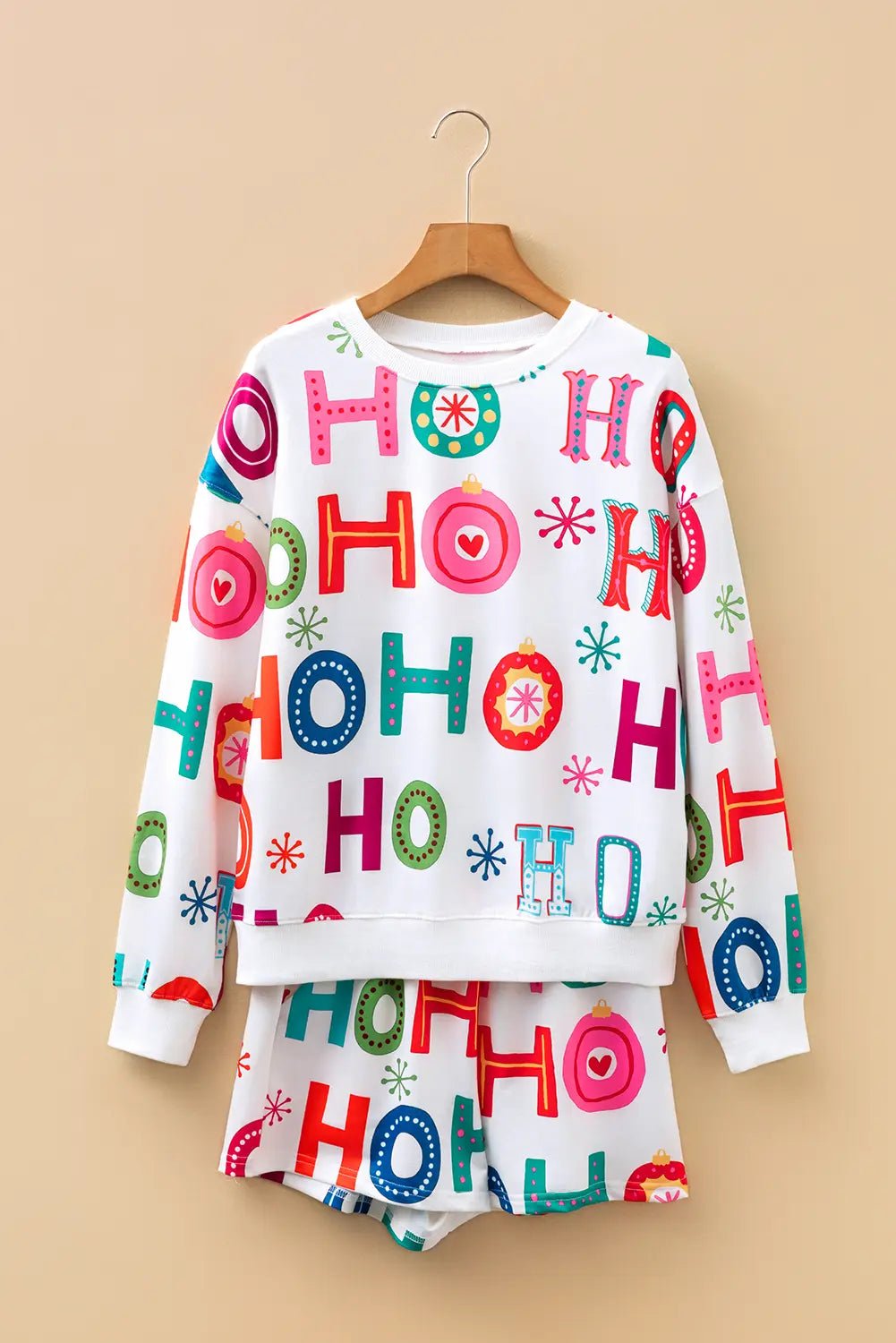Children’s white sweatshirt and shorts set with colorful HO HO HO print on a beige background.