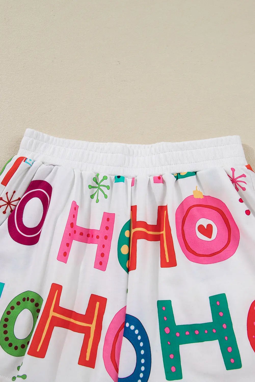 White fabric with colorful 'HO HO HO' text and decorative elements on a beige background