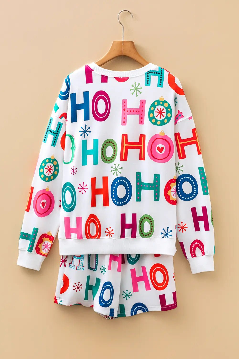 Children’s white sweatshirt and shorts set with colorful HO HO HO print, displayed on a wooden hanger.