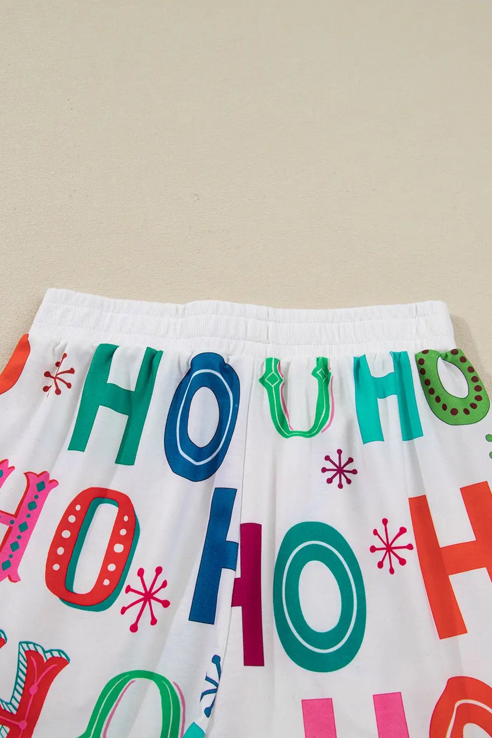White garment with colorful HO HO HO holiday print in red, green, blue, and pink.