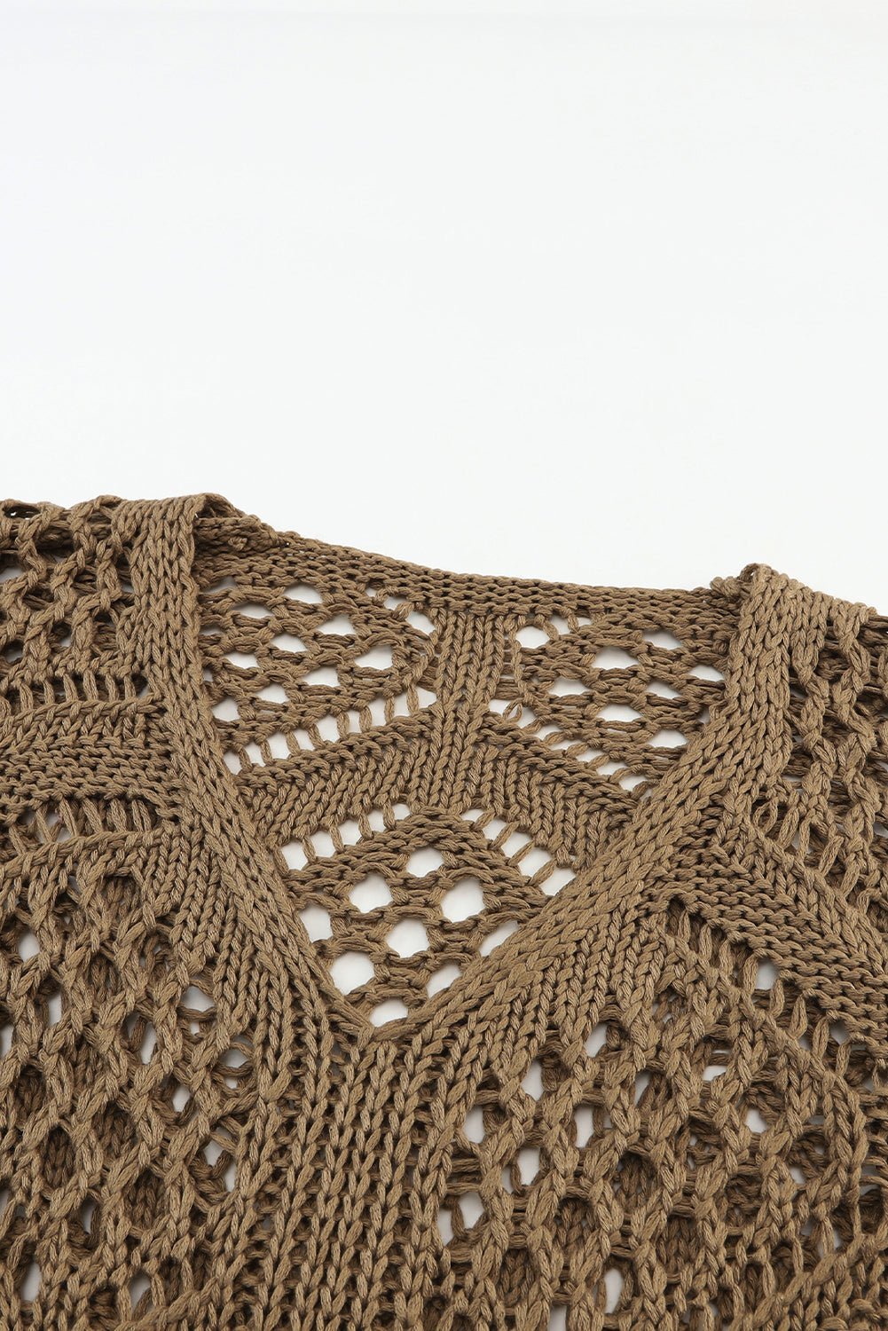 Close-up of a brown knitted garment with intricate pattern on a white background