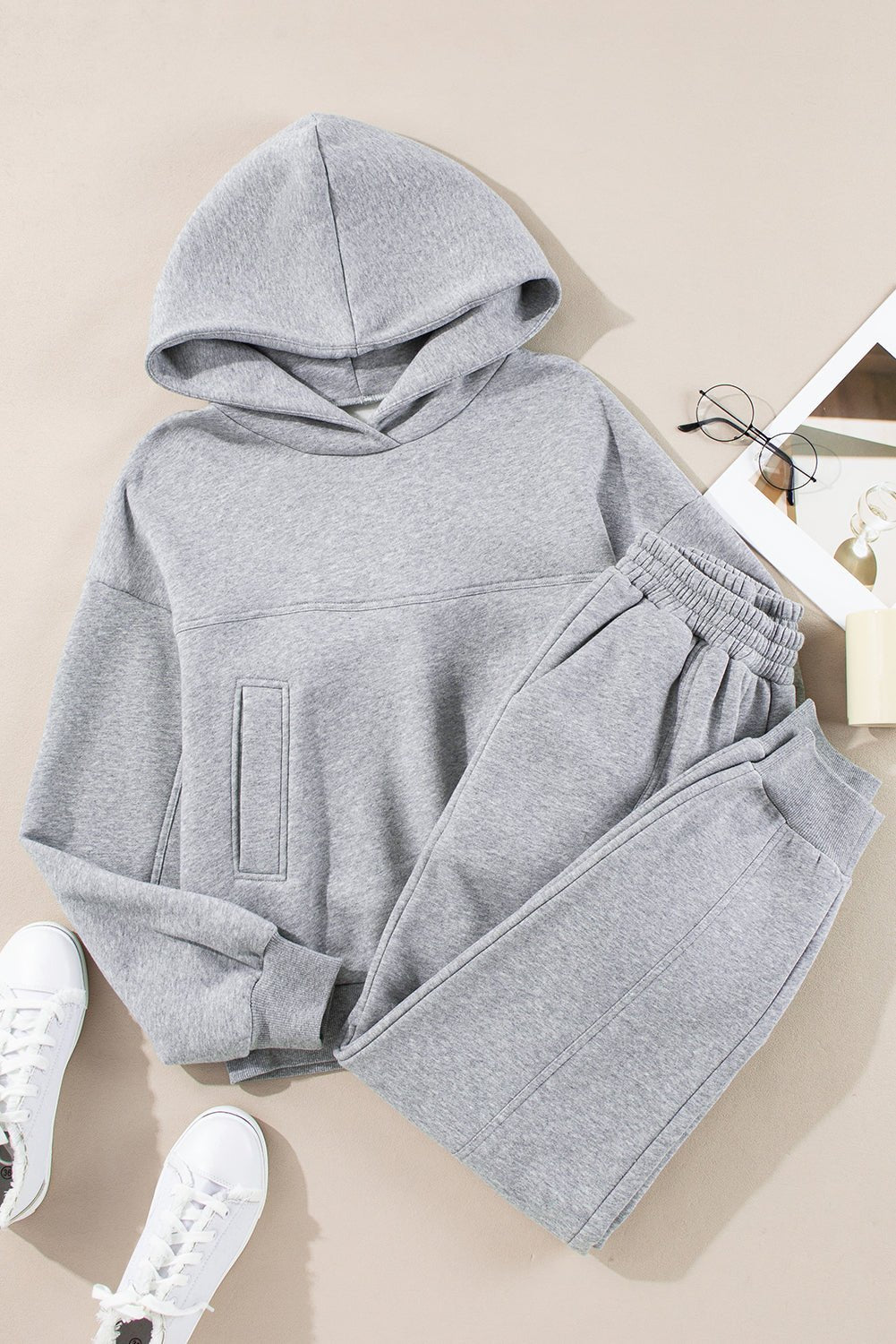 Gray hoodie and pants set with white sneakers on a beige background