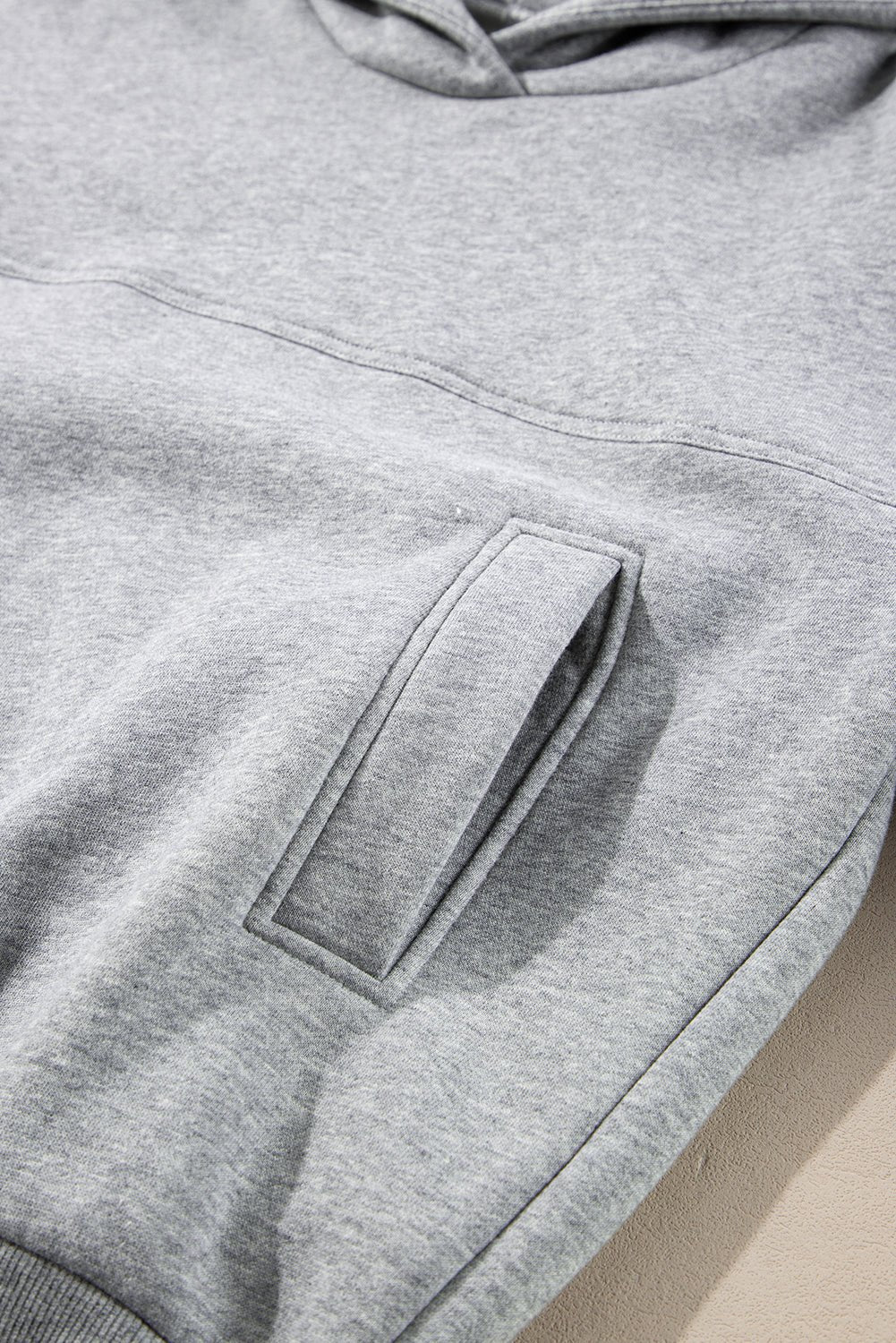 Close-up of a gray hoodie with a pocket on a beige background