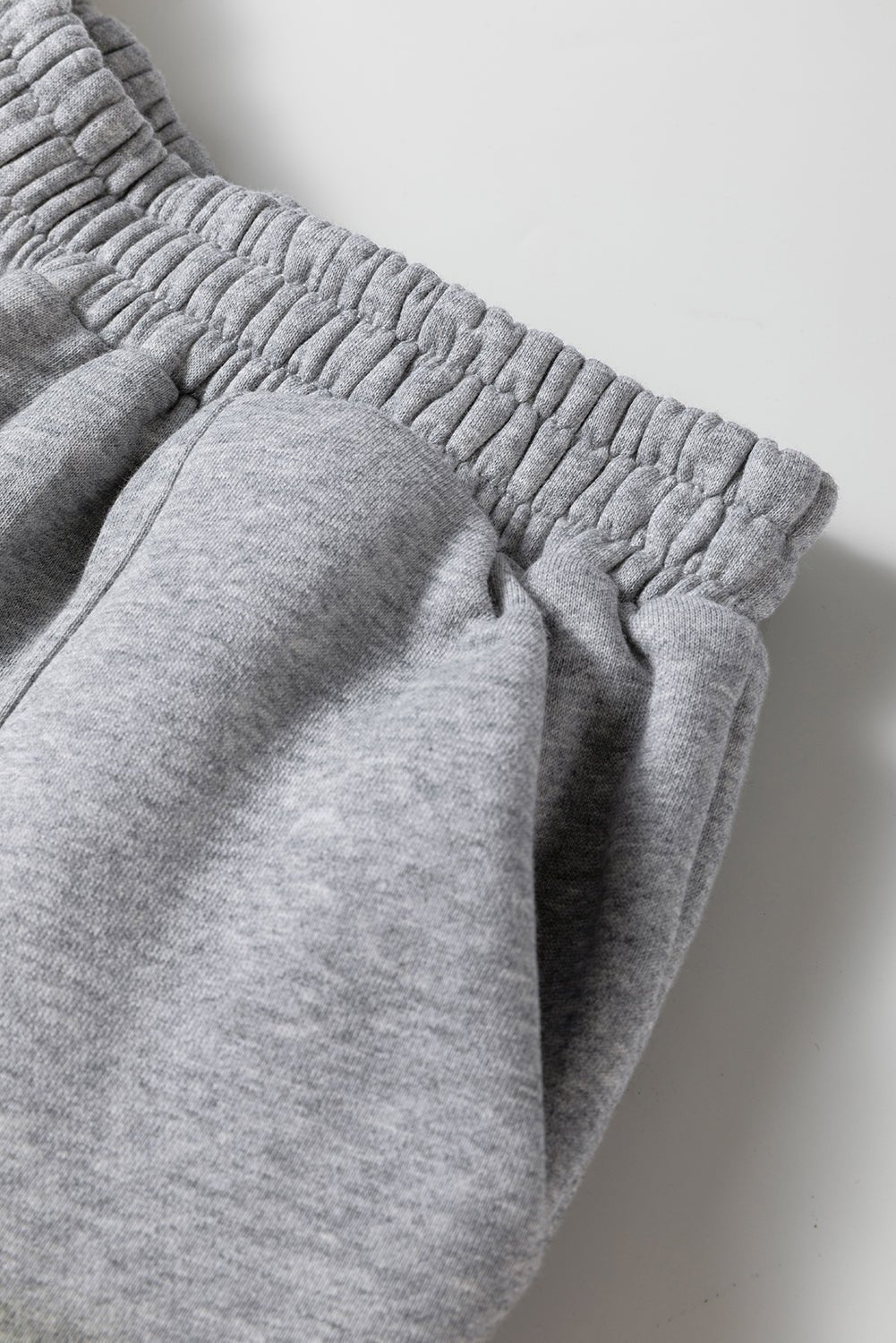 Close-up of gray sweatpants on a light gray background
