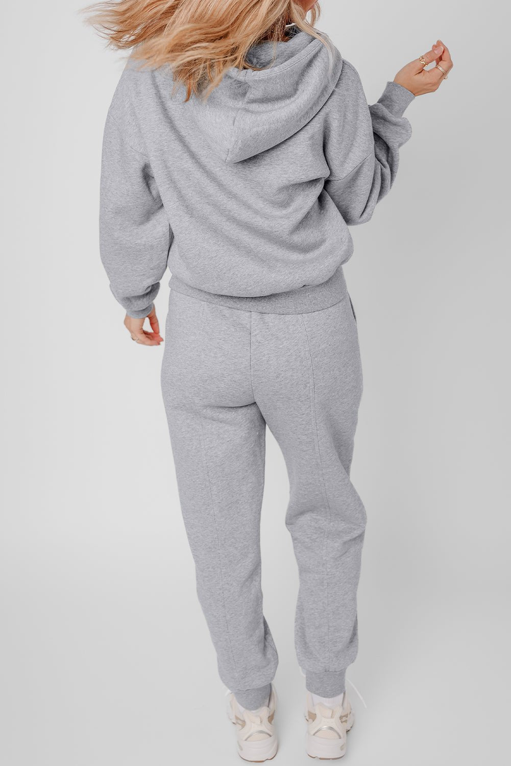 Person wearing a gray tracksuit on a plain background