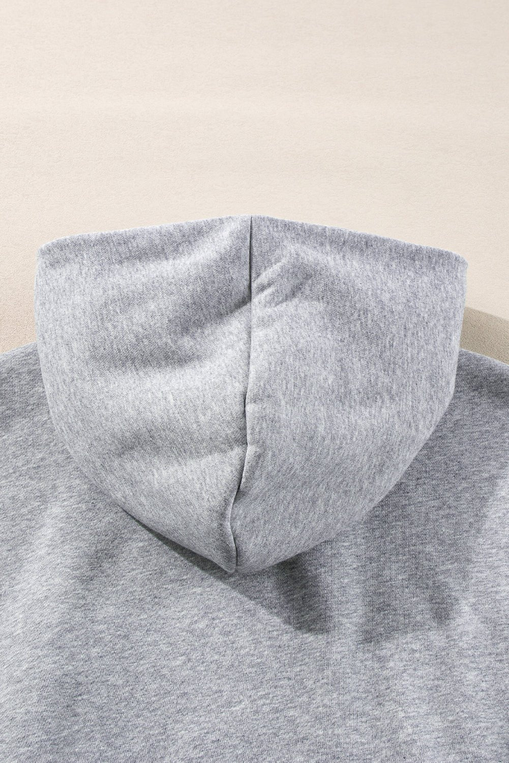 Close-up of a gray hoodie with a hood on a beige background