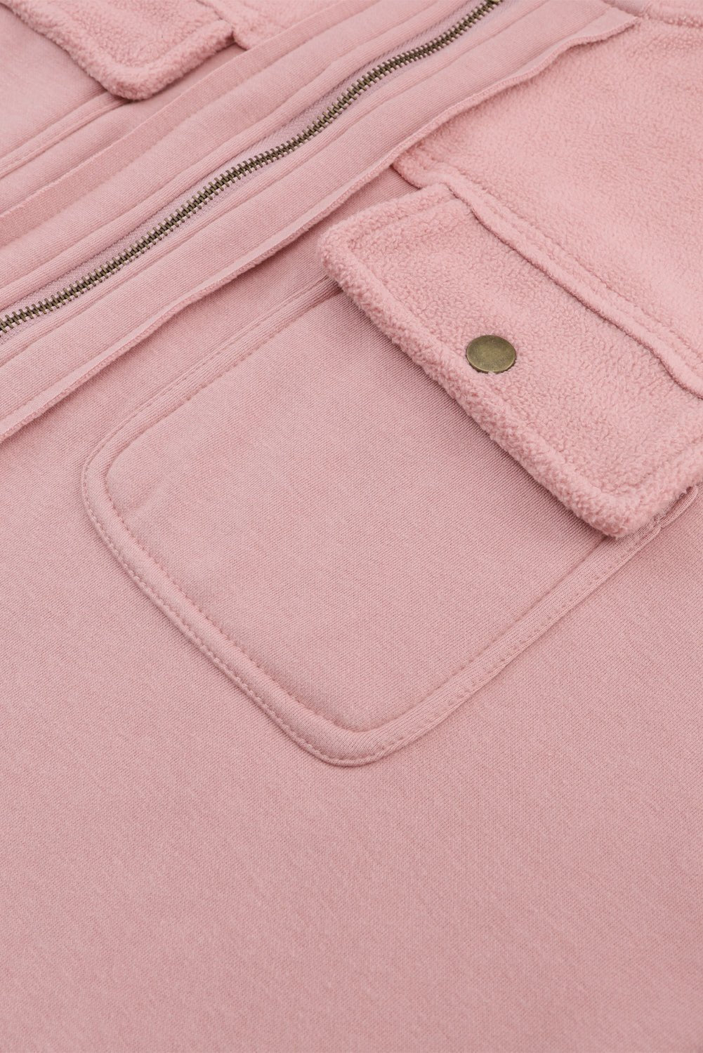 Close-up of a pink jacket with a pocket and zipper detail.