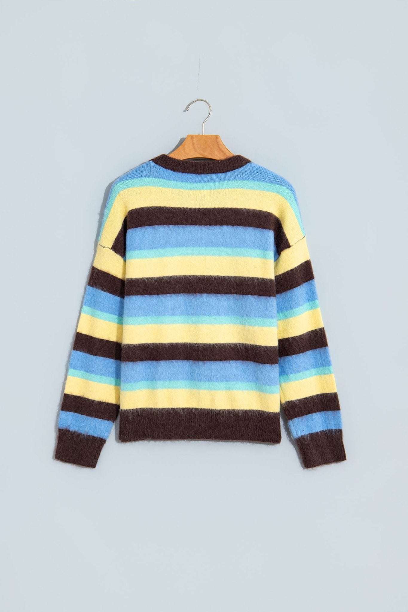 A striped knit sweater with horizontal bands of dark brown, light blue, yellow, and light blue, hanging