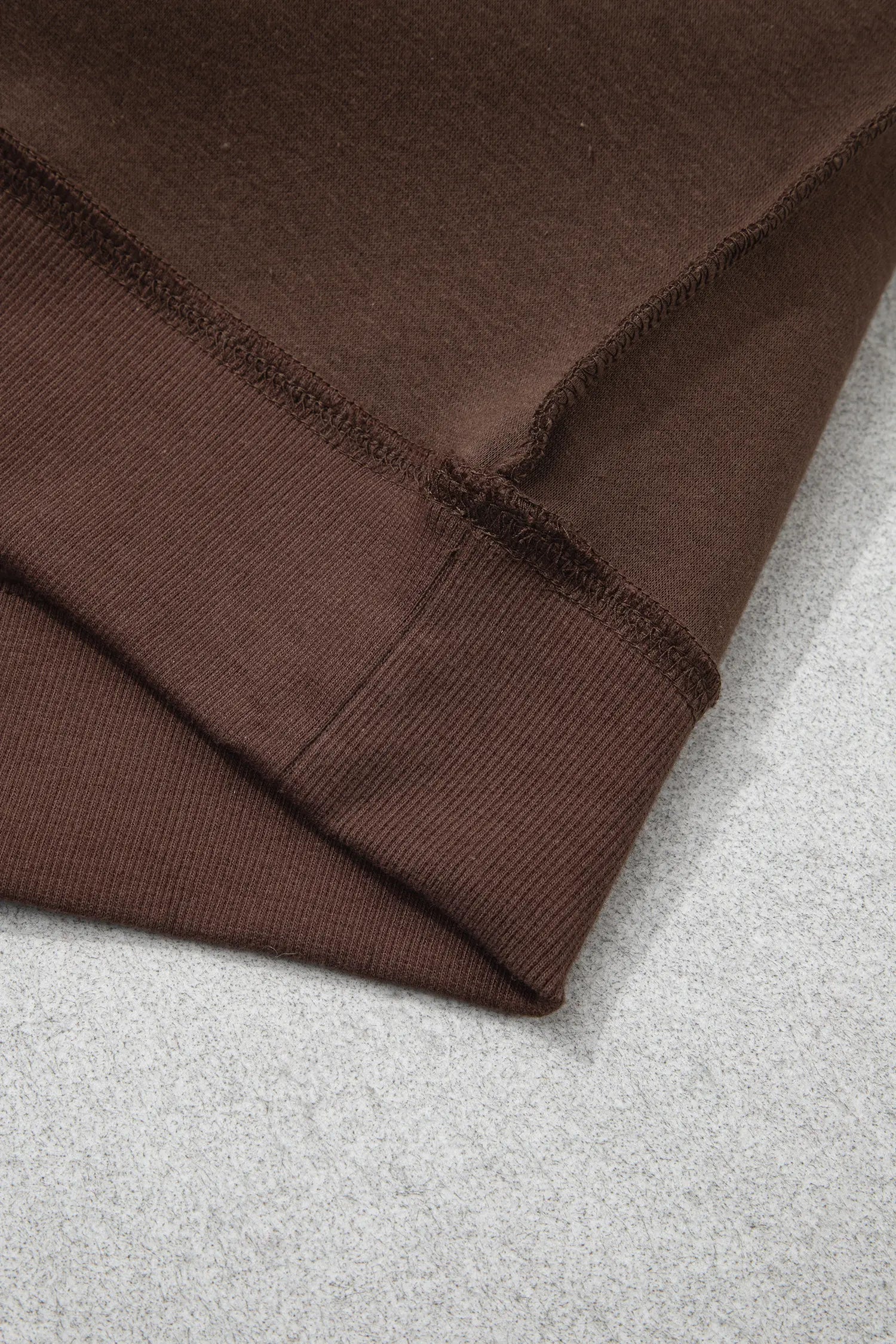 Ribbed hem band with exposed seam on coffee sweatshirt