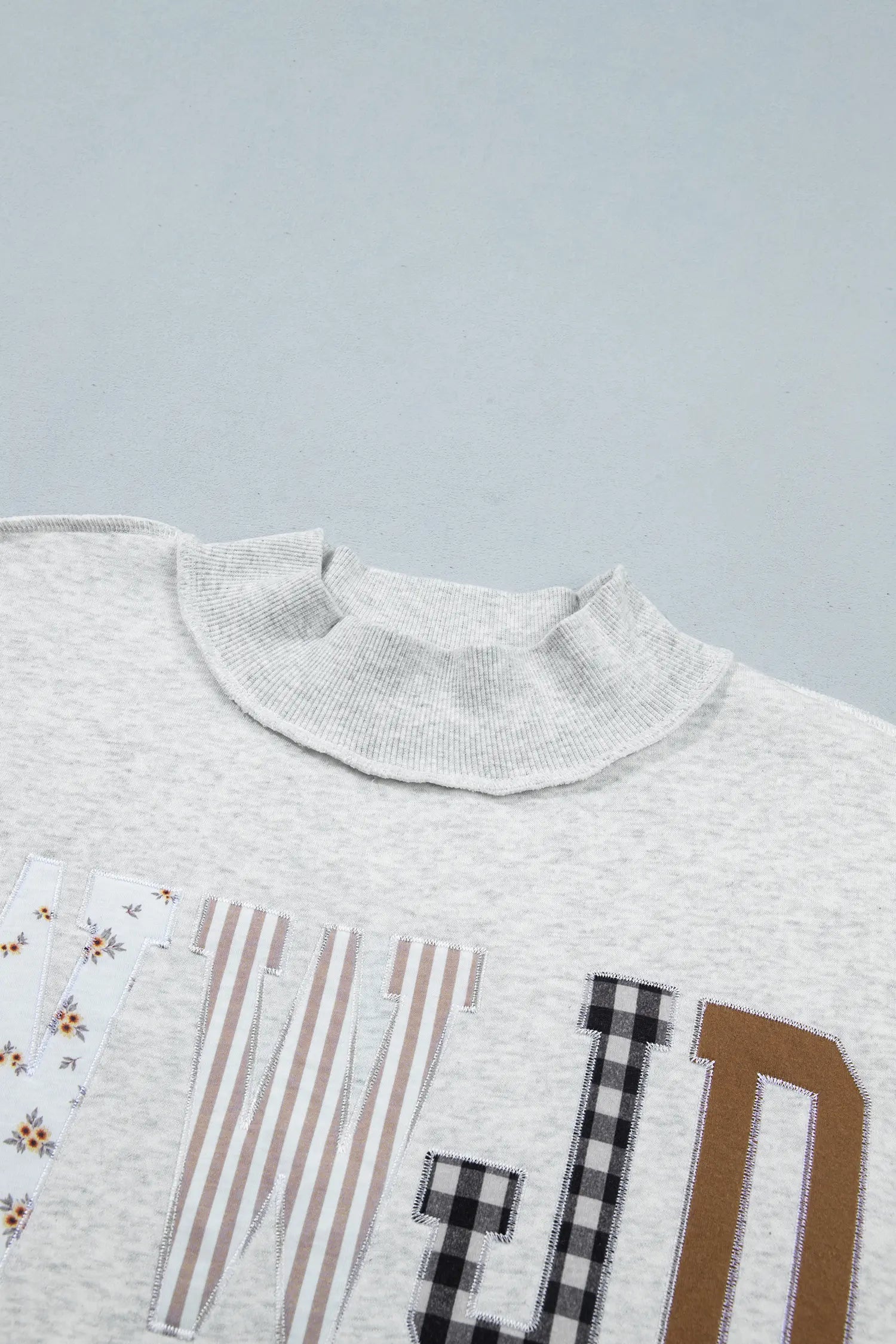 Ribbed mock neck and patchwork letters on gray sweatshirt
