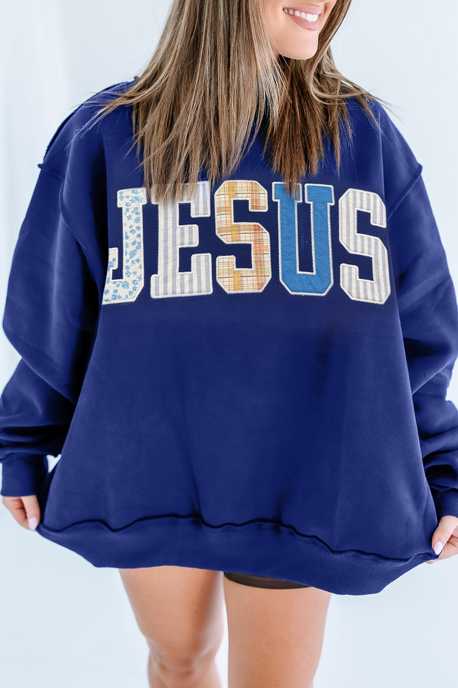 Woman in navy JESUS patchwork letter oversized mock neck sweatshirt, front view