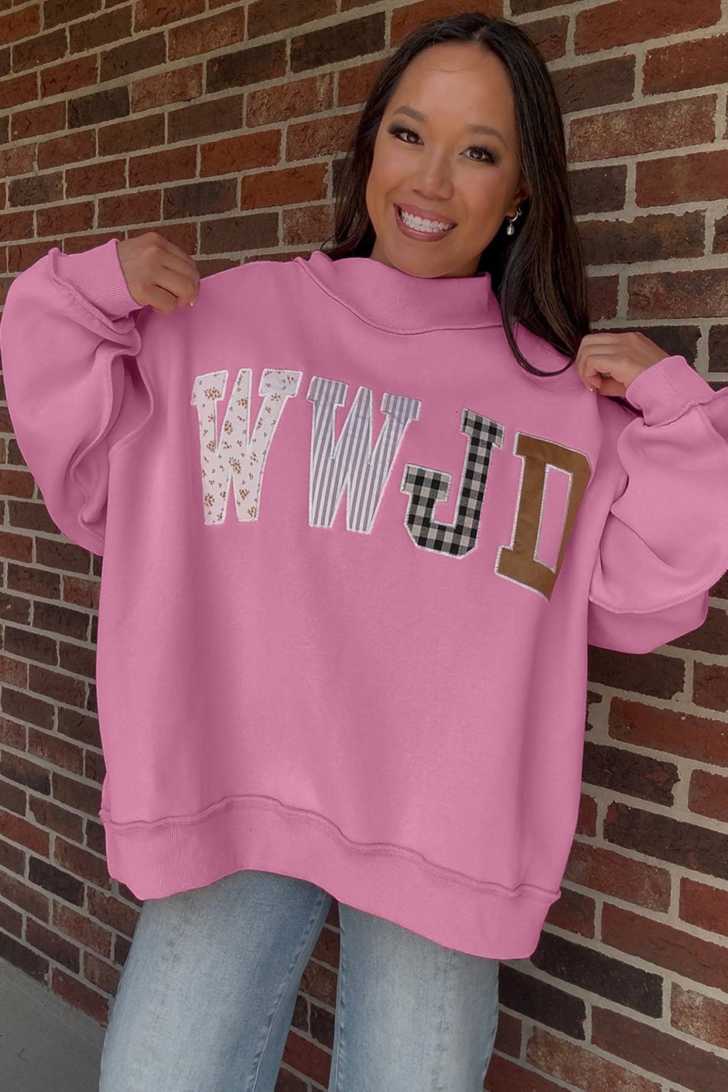 Woman in bonbon pink WWJD patchwork letter sweatshirt with jeans